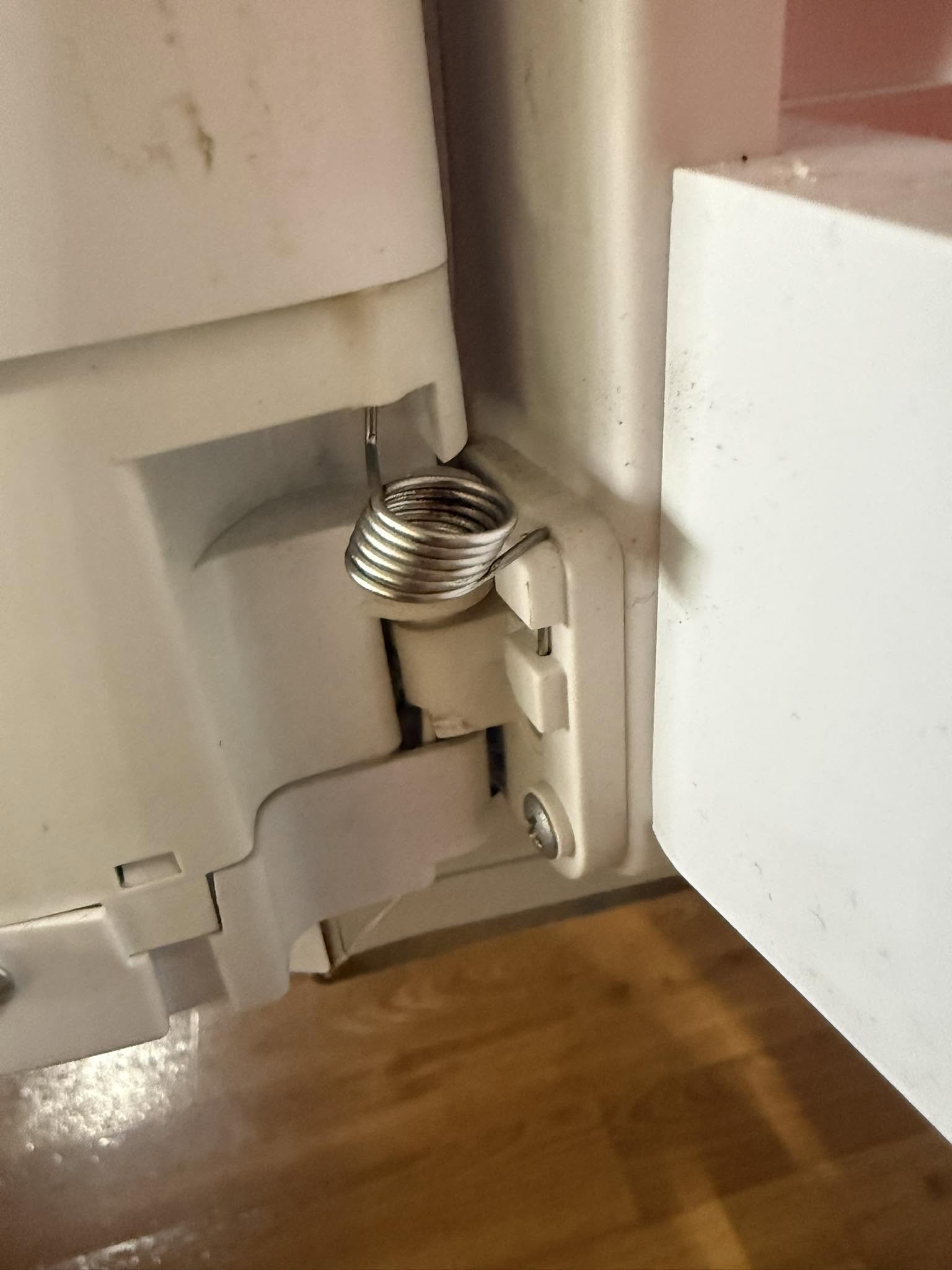 Close up of an appliance door hinge mechanism during a repair